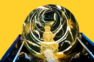 Su parkında kay. Sonu gelmeyen büyük yuvarlak altın renkli su kaydırağının sonunda, sarı arkaplan üzerinde akarsu akan fotokopi alanının olduğu soyut bir yakın çekim. Spa.