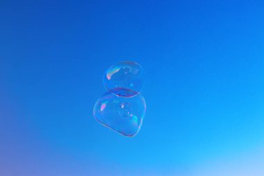 Mavi bir arka planda sabun köpükleri. Havada yüzen büyük kabarcıklar.