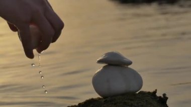 Taşlar gün batımında denizin arka planında dengelenir. Denge ve uyum kavramı. Zen taşlarını gün batımında denizin arka planına yığmak..