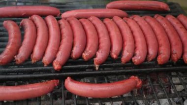 Lezzetli, sulu sosisler ateşin üstünde ızgara yapıyor. Yaz pikniğinde barbekü.