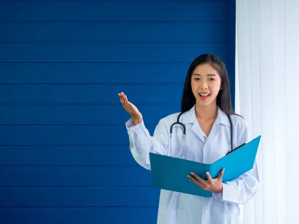 Χαμογελώντας Όμορφη Ασιατική Γυναίκα Γιατρός Πορτρέτο Στέκεται Μπλε Φόντο Κρατώντας — Φωτογραφία Αρχείου
