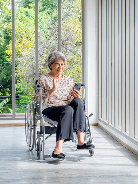 Ευτυχισμένη Ασιάτισσα Ηλικιωμένη Κάθεται Αναπηρικό Καροτσάκι Χαιρετώντας Χαμογελώντας Και Κοιτάζοντας — Φωτογραφία Αρχείου