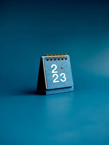 Happy new year 2023 background. 2023 numbers year with target icon on blue small desk calendar cover standing on blue background, vertical style. Business goals and success concepts.