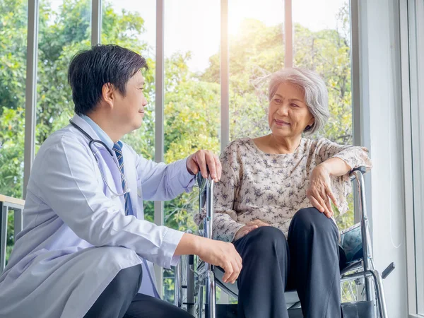 Uśmiechnięty Azjata Lekarz Białym Płaszczu Rozmawia Pacjentką Podeszłym Wieku Która — Zdjęcie stockowe