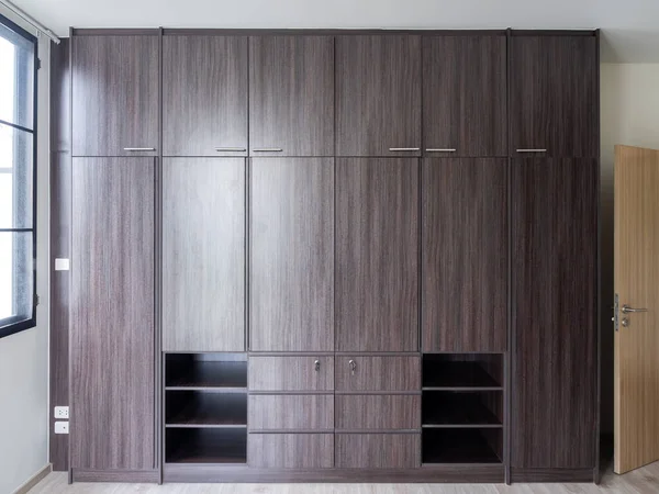 现代的巨大的棕色木制衣柜在白色的房间 新房子靠窗的墙上有内嵌的橱柜家具 简朴的室内设计 — 图库照片