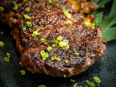 Yakın plan Avustralya dilimlenmiş orta pişmiş wagyu ızgara biftek üstü ve koyu arka planda cam tabakta doğranmış taze soğan. Japon usulü. Avustralya ızgara et dokusu.
