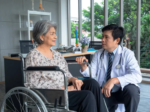 Uśmiechnięta Azjatycka Starsza Pacjentka Siedząca Wózku Inwalidzkim Rozmawiająca Przyjaznym Lekarzem — Zdjęcie stockowe