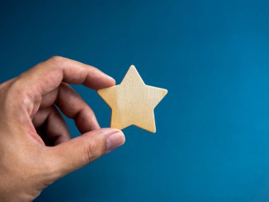 Mavi arka planda izole edilmiş ahşap bir yıldız. Başarı ve refah, müşteri derecesi, kalite, ödül kavramları.