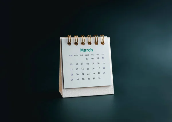 A March 2023 calendar desk for the organizer to plan and reminder isolated on dark green background, minimal style. White small table calendar with the page of the third month.