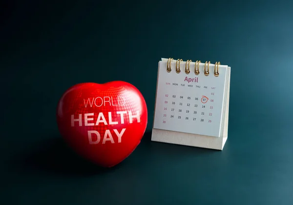 World Health Day concept. World health day, text on world map on red heart ball and April 2023 page, desk calendar with circle mark on day friday 7th, isolated on dark green background.