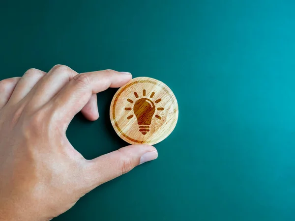 Green ecology, Inspiration and creative system management and environment development for sustainable concepts. Creative idea light bulb icon on round wooden block in hand on blue green background.