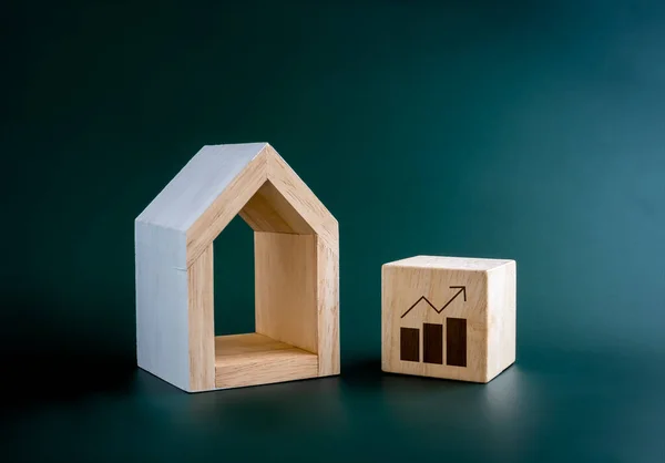 Home interest rate, property price, mortgage, tax, financial, loan, investment housing real estate concepts. Growth graph icon on wooden cube block near minimal wood house model on blue background.