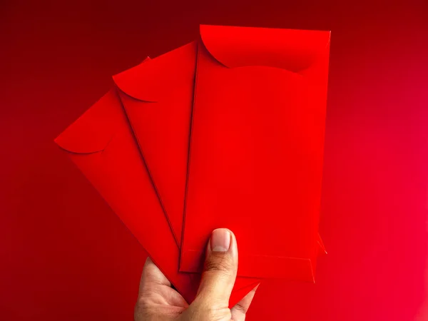 Три Красных Конверта Держатся Вручную Изолированы Красном Фоне Hongbao Пакеты — стоковое фото