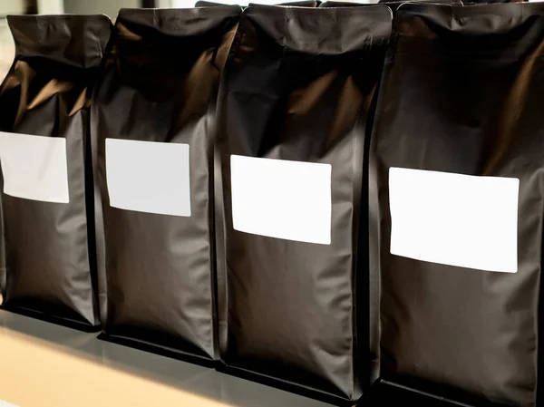 关闭空白空白标签在现代黑色包咖啡豆包装 模型模板贴纸标签 货架上摆放着一排装咖啡豆的纸拉链袋包装 — 图库照片