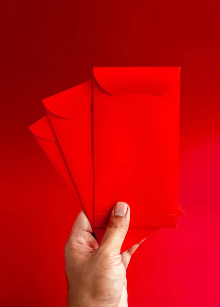 Три Красных Конверта Держатся Вручную Изолированы Красном Фоне Вертикальный Стиль — стоковое фото