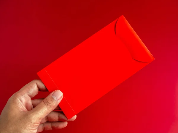 Mano Che Tiene Una Busta Rossa Isolata Sfondo Rosso Pacchetto — Foto Stock