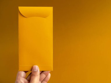 Elinde altın bir zarf var, dikey stil, sarı arka planda izole edilmiş, fotokopi alanı var. Çin 'de uğurlu para hediyesi için Hongbao paketi, Ocak' ta yeni yıl, özel paket..