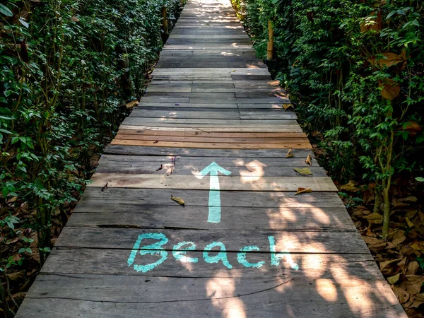 夏休みの休暇のコンセプト テキスト ビーチ の手書きのフォントをリラックスし 熱帯ジャングルの背景にビーチの海に向かう古い木製の橋に描かれた真っ直ぐに矢印アクアブルーの色の手 — ストック写真