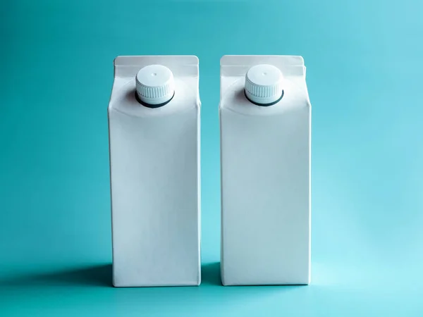 两杯白牛奶或饮用水的调味盒 每升1升 螺丝盖隔离在蓝色背景下 垂直风格 照片上白色透明的空牛奶盒 前面有空白的地方 — 图库照片