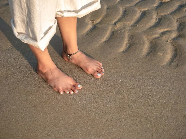 傍晚时分 穿着白色裤子 双腿交叉的赤脚女子站在清静的沙滩上 沐浴在温暖的阳光下 有着复制的空间 暑期旅行 休闲目的地和度假概念 — 图库照片