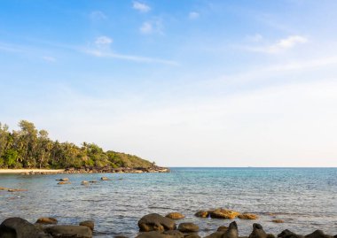 Güneşli bir günde parlak deniz manzarası. Yaz arkaplanı plaj kayaları, ada, berrak deniz suyu ve açık mavi gökyüzü güneş ışığı günü, yaz manzarası, tatil posterleri.