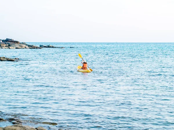 身穿救生衣 头戴礼帽的亚洲女人的背 乘黄色的皮划艇在海上划桨 快乐的女性 在海景 度假等背景下进行有趣的活动 — 图库照片