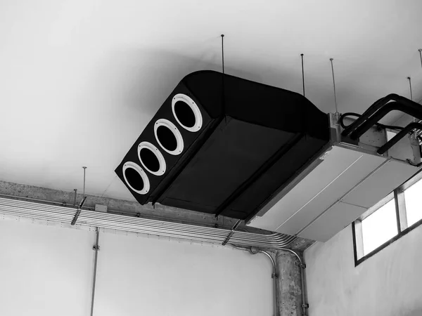 ブラックマシン 近代的な空調天井は 古い白い建設ビル工場 ロフトスタイルのインテリアで電気配線鋼管の近くの天井に換気システムの装飾を取り付けました — ストック写真