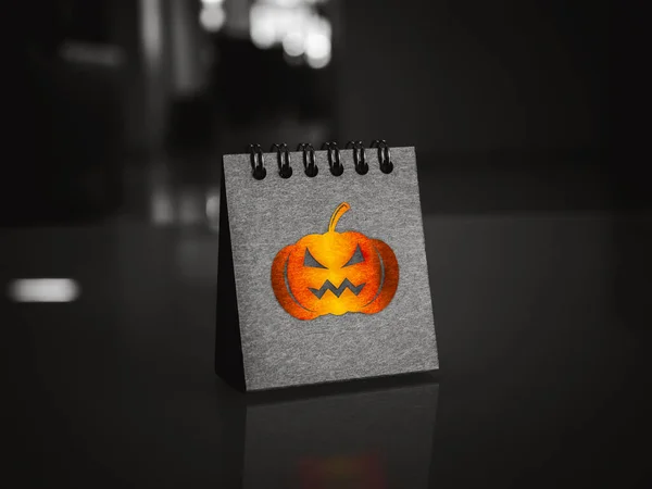 Happy Halloween day calendar with shiny pumpkin graphic icon on black folding desk calendar standing on desk on dark background. Trick or treat festival party and holiday concepts.
