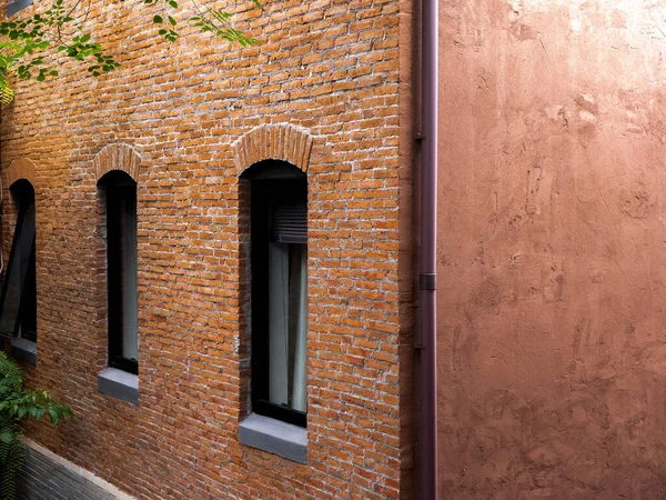 Beautiful vintage red bricks building exterior design, decorated with curved glass windows, brown pipeline. Earth tone old building design with red color cement background.