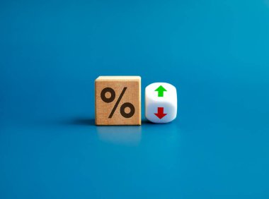 Percentage icon on wooden cube block and up and down arrow symbol on flipping white dice on blue background. Interest rate, financial stocks, ranking, GDP percent change, money exchange concepts. clipart