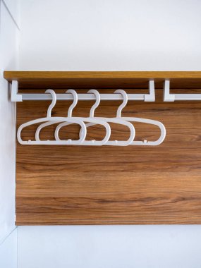 Beyaz arka planda tahta bir gardıropta, gömleksiz ya da elbisesiz dört boş plastik elbise askısı otel odasında kalan konuğumuz için hazırlanıyor..