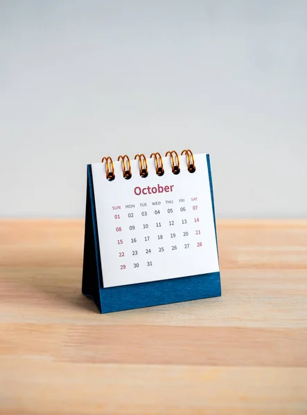 An October 2023 calendar desk for the organizer to plan and reminder isolated on wood table and white background, vertical style, minimal style. Blue small table calendar with page of the 10th month.