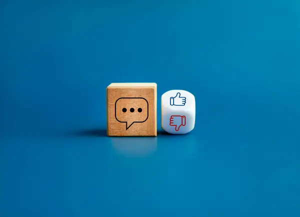 Social media online comment, social network post agree concept. Comment icon on wooden cube block, like and unlike hand symbol on flipping white dice isolated on blue background, minimal style.