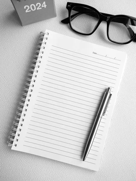 To do list, goals and target concept in new year 2024. Mockup template white blank space on spiral diary notepad with pen and 2024 year desk calendar and glasses on white background, vertical style.