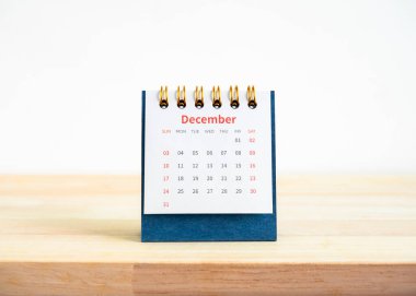 Ahşap masa ve beyaz zemin üzerinde izole planlama planı için 2023 masa takviminin Aralık sayfasındaki sayfa. 12. ayın sayfası ile mavi küçük masa takviminin ön görünümü.