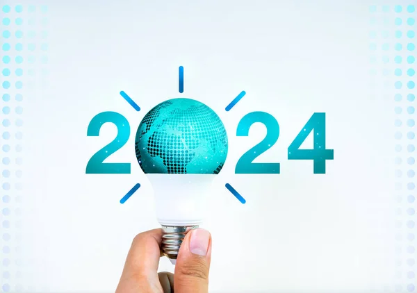 Green 2024 year numbers with creative trend light bulb assemble with earth holding by hand on white . Happy 2024 New Year greeting card with world light bulb, innovation and creative trends concept.