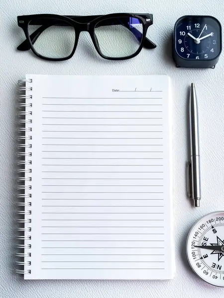 To do list, goals and target concept in new page notebook. Mockup template white blank space on spiral diary notepad with pen ,clock, compass and glasses on white background, vertical style.