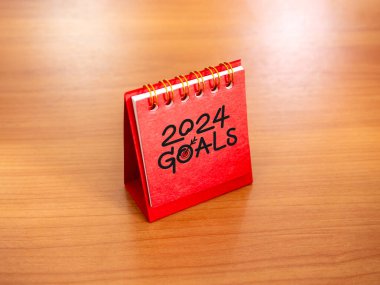 Yeni yıl 2024 afiş arkaplanına başla. El yazısıyla yazılmış metinler, hedefler ve hedef simgesiyle ahşap masanın üzerinde duran 2024 numara yılı. İş hedefleri ve başarı kavramları.