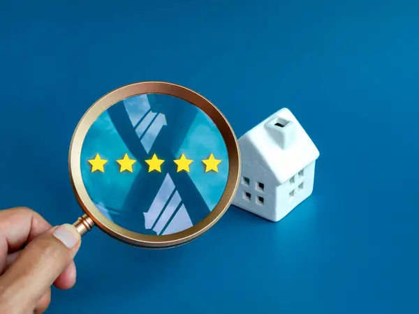 Quality home and land survey, house rating and feedback online, searching real estate website, property investment concepts. Five stars review in magnifier lens near white house on blue background.