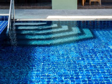 Yüzme havuzu merdivenleri, temiz su yüzeyi geçmişi, hiç kimse. Soyut havuz dokusu, su altı desenli mavi arka plan ve bar merdiveni, insan yok. Yaz arkaplanı.