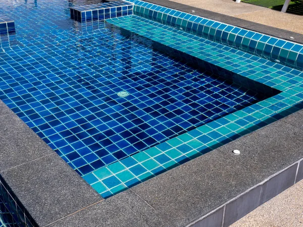 Floating bench seat, sitting zone in swimming pool with clean clear water, nobody. Square shaped pool with blue tiles, no people. Summer background.