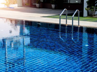 Temiz su yüzeyi geçmişi olan yüzme havuzu merdiveni, kimse yok. Soyut havuz dokusu, su altı desenli mavi arka plan ve bar merdiveni, insan yok. Genel bakış. Yaz arkaplanı.