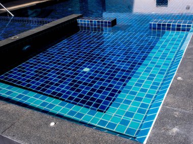 Yüzme havuzunda oturacak bir yer, temiz su, hiç kimse. Mavi karoları olan kare şeklinde bir havuz, insan yok. Yaz arkaplanı.