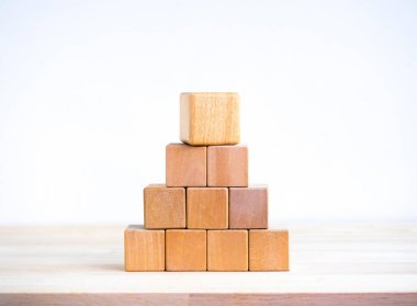 Boş boş tahta küp bloklar piramit şeklini oluşturur. Üstünde büyük olan beyaz arka plandaki ahşap masada izole edilir. İş büyüme süreci, eğitim, başarı binaları ve organizasyon kavramları.