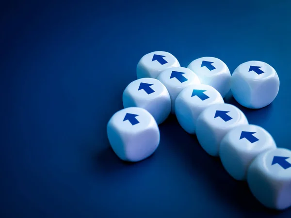 Leadership, go to success, business team progress, teamwork, advances in technology concept. Close-up straight arrows icon symbol on white dice block built as heading arrow shape on blue background.