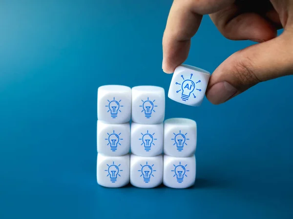 AI digital innovation service, creative idea support, working with technology concepts. Artificial intelligence in lightbulb icon piece in hand put on block group of idea light bulb symbol on blue.