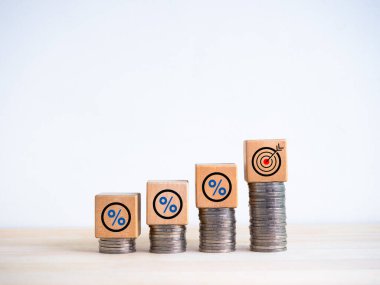 Tahta küp bloklardaki hedef ve yüzde simgesi beyaz arka planda izole edilmiş bozuk para yığınlı bar grafik çizelgesi basamaklarında. Yatırım, kâr, gelir, satış, iş büyümesi, ekonomik iyileştirme kavramları.