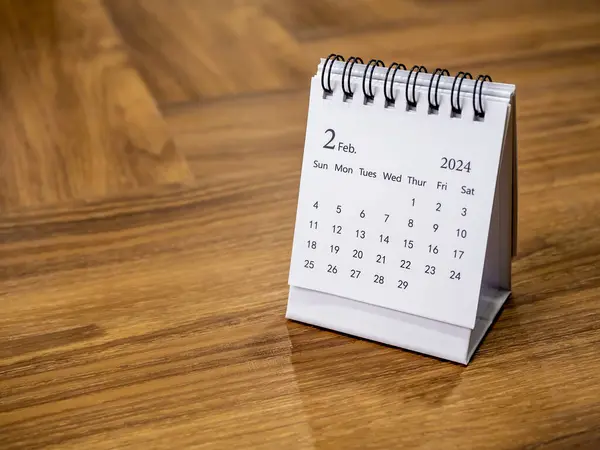 A February 2024 on calendar desk for the organizer to plan and reminder on wood background with space, minimal style. White small table calendar with the page of the second month, Happy new year 2024.