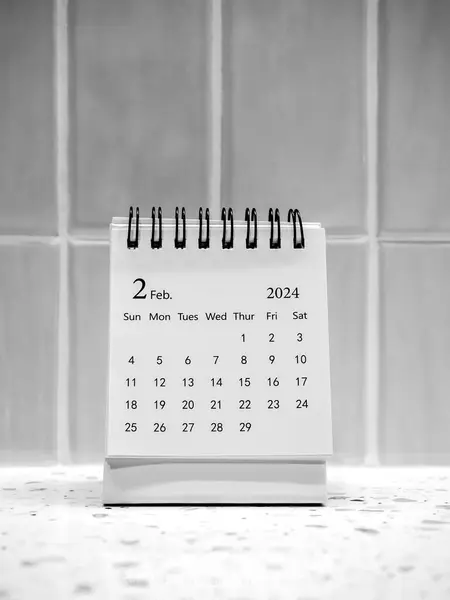 A February 2024 on calendar desk for organizer to plan and reminder on vertical white tiles background, minimal style. White small table calendar with page of the second month, Happy new year 2024.