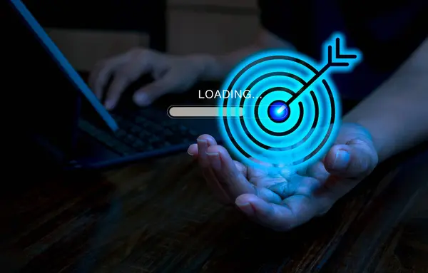 Blue digital goal target dart icon with loading bar in businessman hand while working with laptop computer. Business startup development with future innovation technology, goal and success concept.